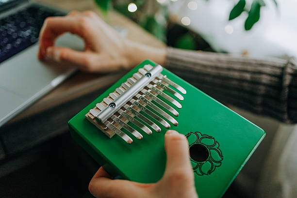 istock Musician performing green kalimba, fingers gracefully tapping metal tines while working on laptop, combining musical creativity with digital productivity in warm home environment 2248400542