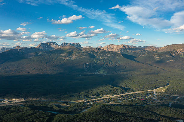 istock Mountain peaks surrounded by dense forest and road, against blue white sky. British Columbia, Canada 2248401319