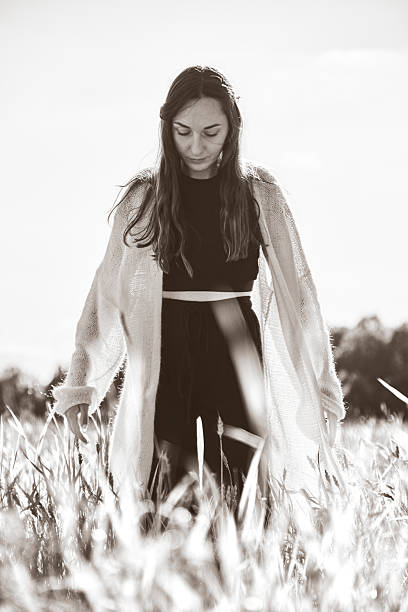istock Woman standing thoughtfully in rye field with sunlight backlighting 2248401489