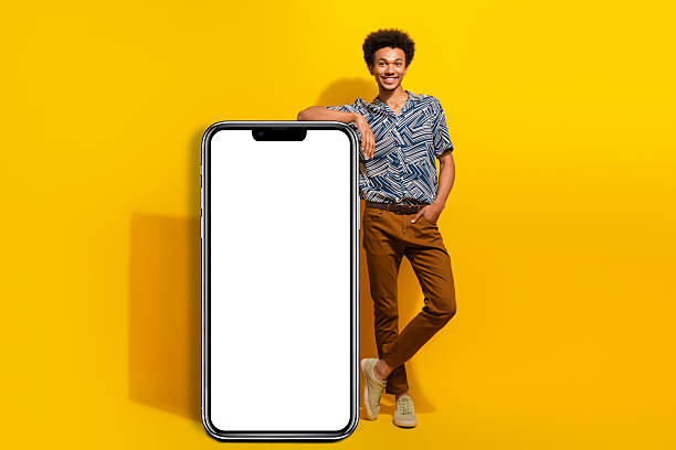 istock Cheerful young man leaning on a white panel against a yellow background, showcasing a stylish look and lively energy 2248401499
