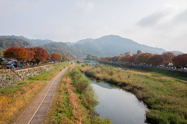 istock Autumn river landscape with vibrant fall foliage lining a paved walking path and distant mountains 2248401558