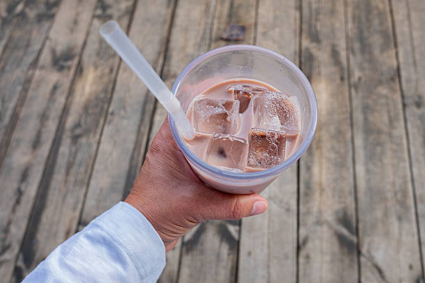 istock Hand holding iced coffee drink with straw over rustic wooden deck, enjoying refreshing cold beverage outdoors 2248401660