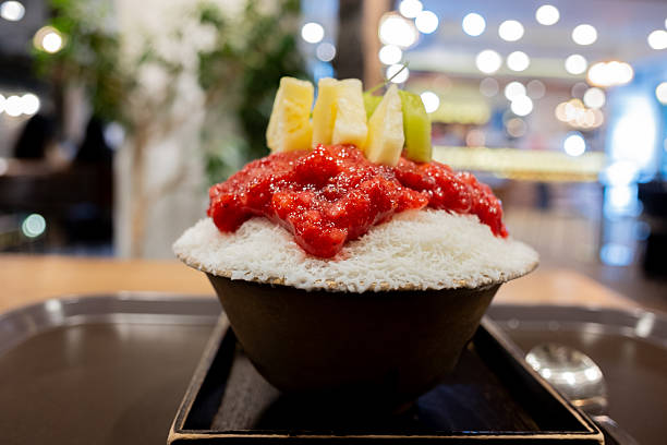 Chilled fruity treat featuring shaved ice, sweet strawberries, juicy pineapple pieces, and a green grape, all beautifully presented in a bowl