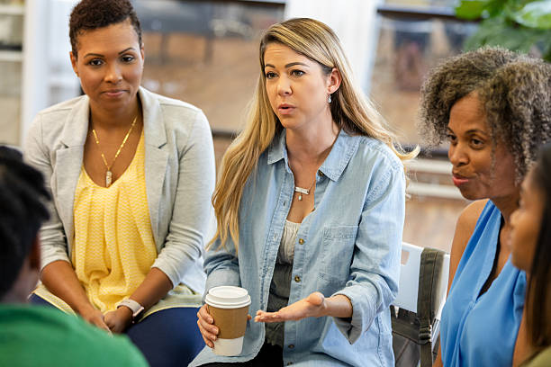 istock Women of diverse backgrounds engaged in supportive conversation during a group meeting. 2248402036