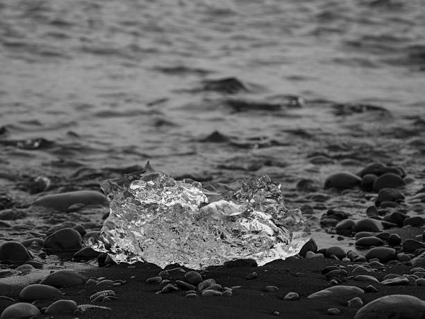 block of ice on black and volcanic sand