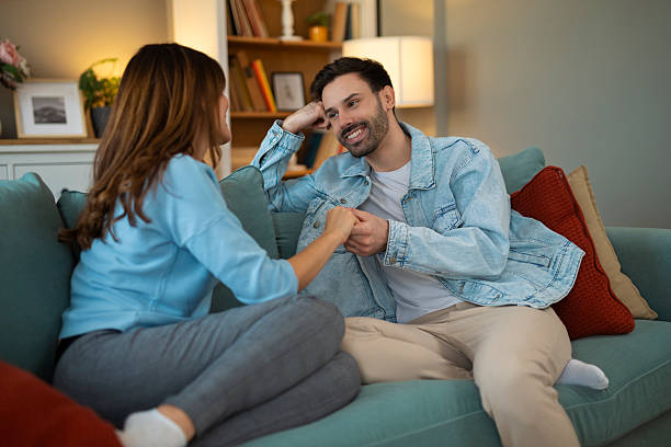 istock Couple holding hands talking on sofa at home 2248403956