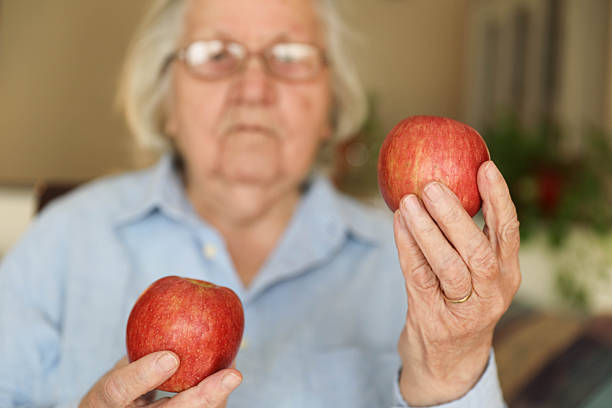 istock Senior Woman Choosing Between Two Red Apples at Home 2248404972