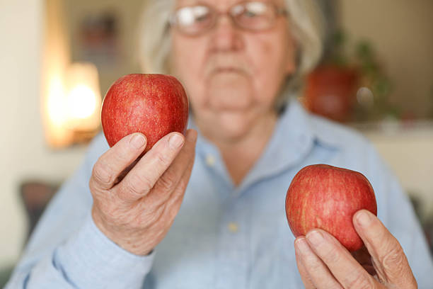 istock Elderly Woman Comparing Apples for Healthy Nutrition 2248404995