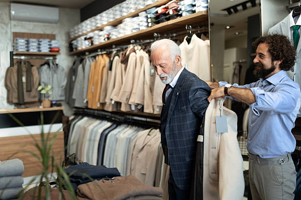 istock Stylish Elderly Man Trying On Clothes with Help from Retail Worker 2248405131