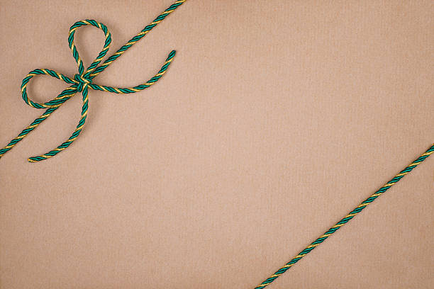 Green and Gold Christmas String Tied in Bow on Kraft Paper Background