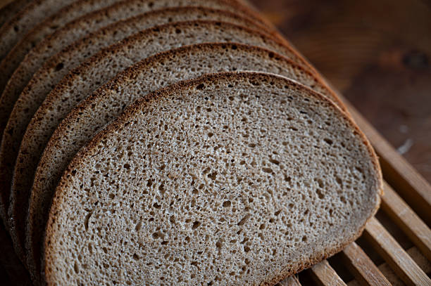 Close-up of freshly sliced whole grain bread arranged on a wooden board and cooling rack. Rustic homemade loaf with natural texture, ideal for concepts of healthy eating, bakery products, organic food, breakfast, and traditional baking.