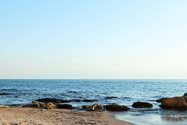 Beautiful wavy sea, stones and sandy beach