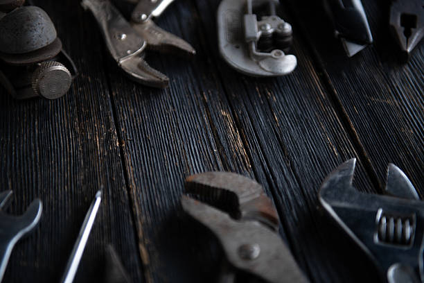 Close-up of old mechanic tools on dark wooden planks with shallow depth of field.