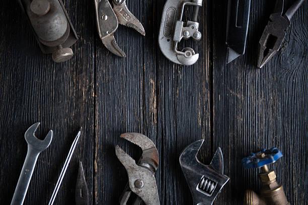 Top view of assorted vintage mechanic tools arranged on a dark rustic wooden background.