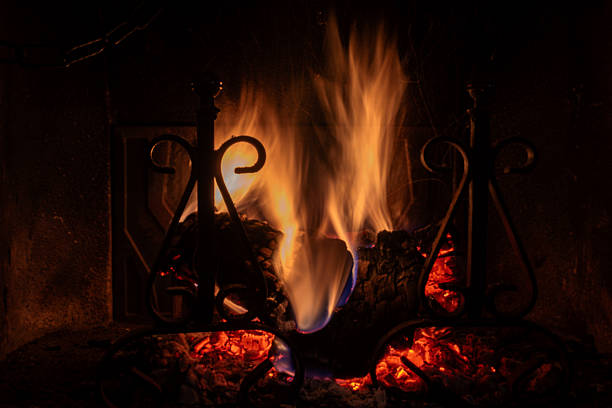 Old fireplace with steel andirons and flames from a wooden strain.