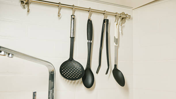 Kitchen utensils hanging on a wall rack for organized cooking space.