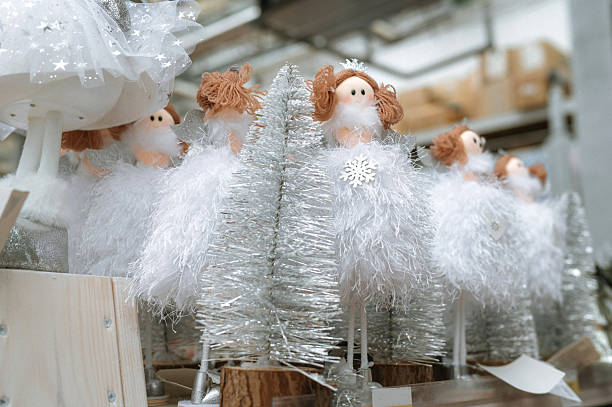 Festive christmas angel dolls with silver trees in winter display.
