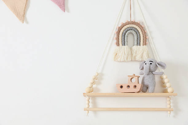 istock Shelf with soft toy elephant and wooden boat on white wall. Space for text 2248417458