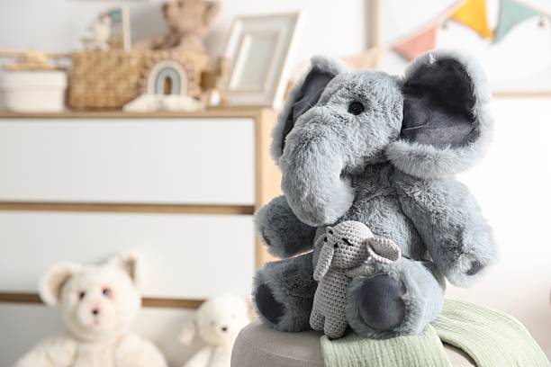 Cute soft toy elephants on pouf in child's room, closeup. Space for text