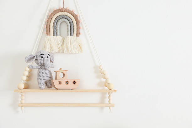 istock Shelf with soft toy elephant and wooden boat on white wall. Space for text 2248417520