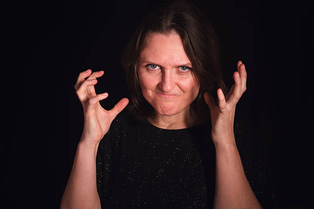 Woman with an angry and frustrated expression and hands raised, demonstrating negative emotion. Concept of stress, anger, and irritation.