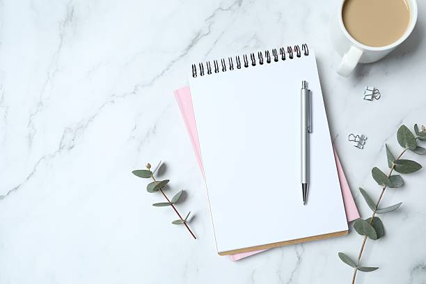 istock Workplace with note, pen and cub of coffee on work table. Top view shot 2248421811