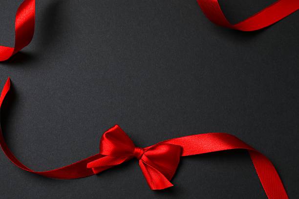 istock Red ribbon and bow on a black background, top view 2248426305