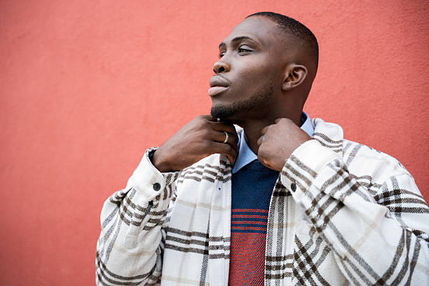 istock Stylish man adjusting his collar in front of a vibrant red wall 2248429809