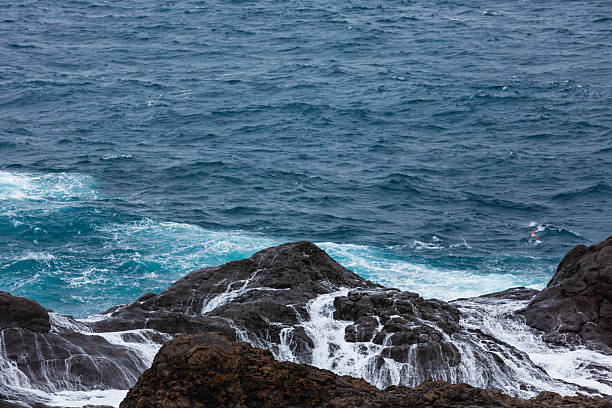 istock Rugged rocky shore meets blue ocean with crashing waves and white foam 2248431110