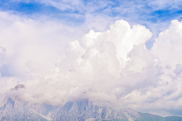 Rugged mountain landscape with dramatic clouds covering the peaks and blue sky above