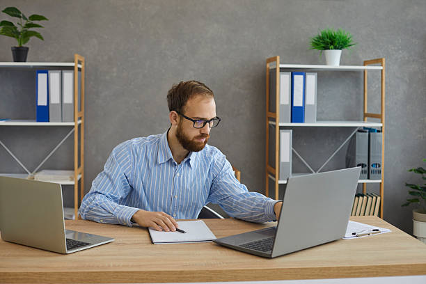 istock Serious young man working on laptop computers sitting at desk in office workplace 2248440237