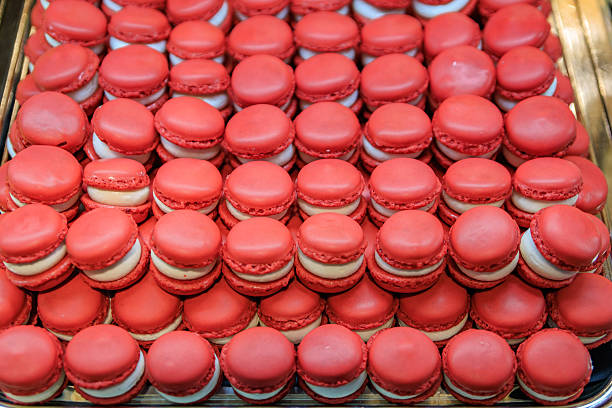 Zurich, Switzerland - November 30, 2024: Rows of small red strawberry Luxemburgerli macarons with cream filling on display at Sprungli chocolatier