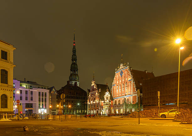 A breathtaking night view of Town Hall Square in Old Riga, Latvia. Historic buildings illuminated against the dark sky, creating a magical atmosphere in this UNESCO World Heritage site.