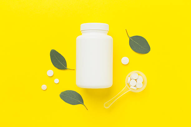 istock Bottle with pills and green leaves on color background, top view 2248449132