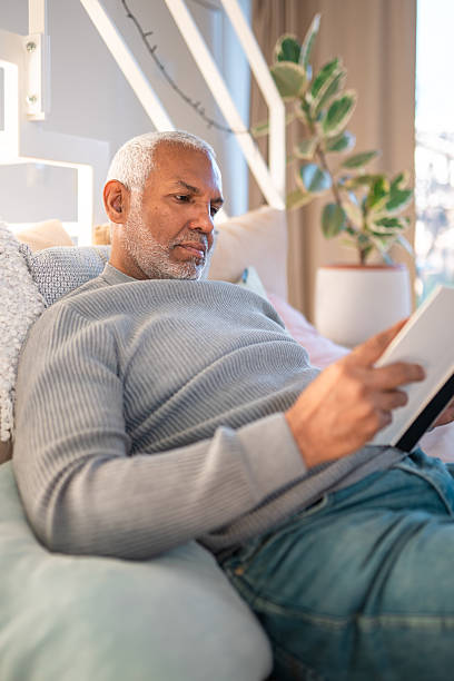 istock Mature Man Reading Digital Device in Sunlit Living Room Setting 2248451640