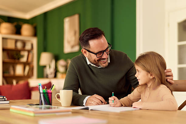 istock Father Helps Daughter With Homework At The Cozy Home Table, Smiling And Engaged 2248451921