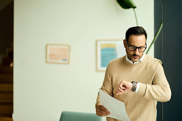 istock Professional Man In Glasses Checks Time While Reviewing Document In Modern Office Setting 2248451941