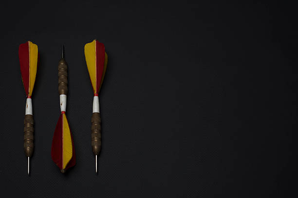 Three high-quality antique darts lying on a black background and in different arrangements