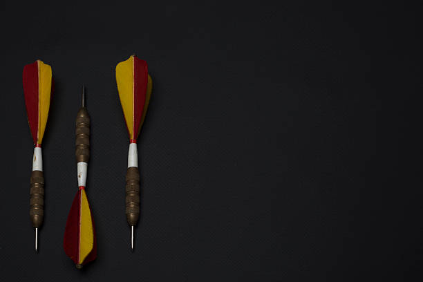 Three high-quality antique darts lying on a black background and in different arrangements