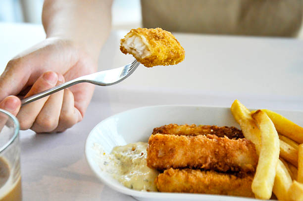 close up of a hand holding a plate of fried potatoes and codfish