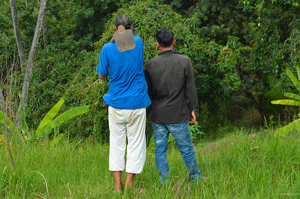 istock Two Farmers Standing on Hillside Observing Mango Trees in Dry Sloping Field 2248462895