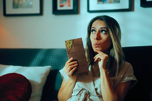 istock Woman In Doubt About Eating a Large Chocolate Bar with Pistachios 2248465221