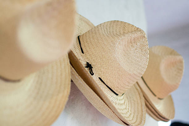 Several straw hats with black bands hanging on a white wall