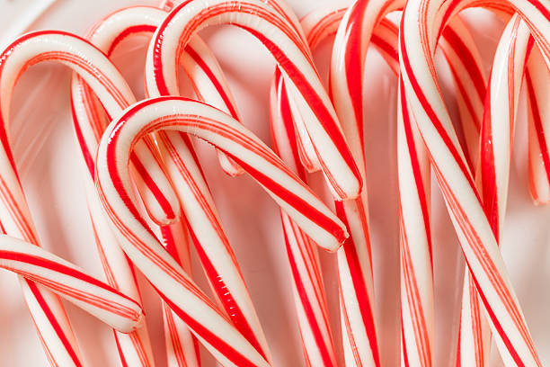 Four red and white striped candy canes are arranged on a wooden surface. Festive colors and natural wood grain create a warm, holiday-themed composition, evoking a sense of unity and seasonal charm