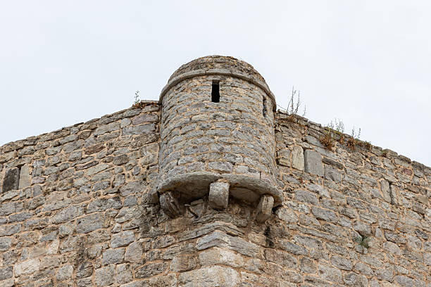 A close view of an old stone wall featuring a rounded turret projecting from a fortress. Citadel of Budva old town, Montenegro