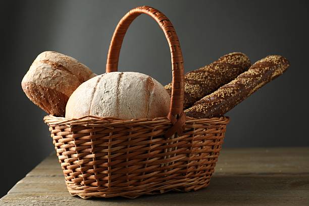 Old fashioned baker organising fresh bread into a traditional basket for delivery and sale