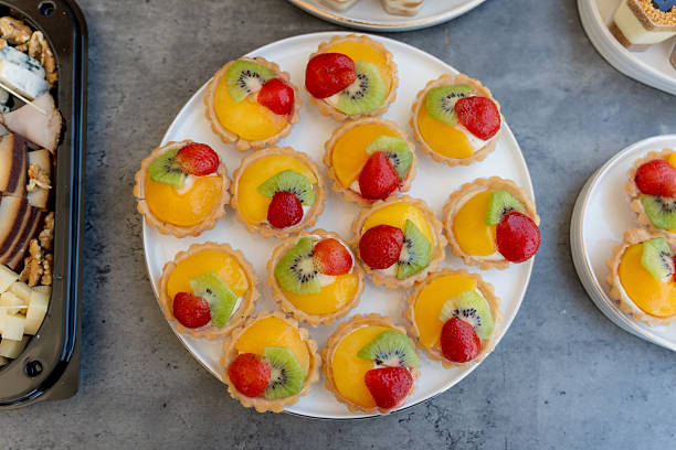 istock Fresh fruit tarts arranged on a white plate at a dessert table during a gathering in the afternoon light 2248472385