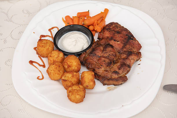 a grilled pork steak with croquettes and carrots