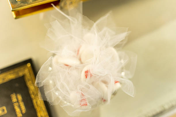 A beautiful white decorative flower made of tulle and adorned with pearls is showcased at a wedding venue, adding a touch of elegance to the setting. The soft background enhances its charm.