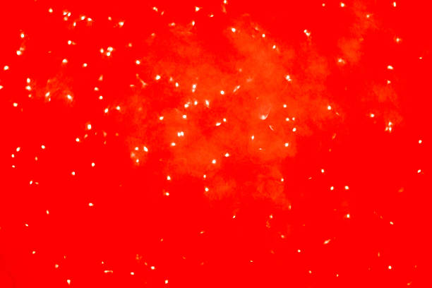 Abstract blurred background in red with scattered bright lights. Represents holiday spirit, winter, Christmas, and New Year celebrations.